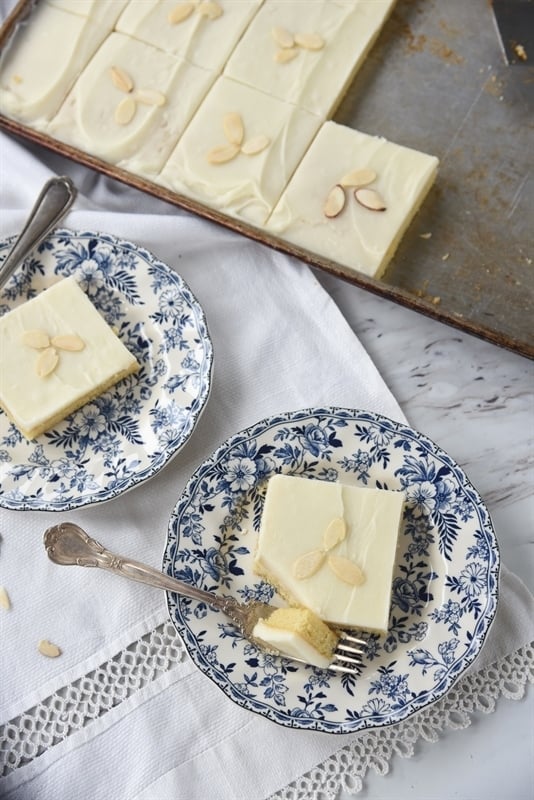 two plates of white texas sheet cake topped with slivered almonds
