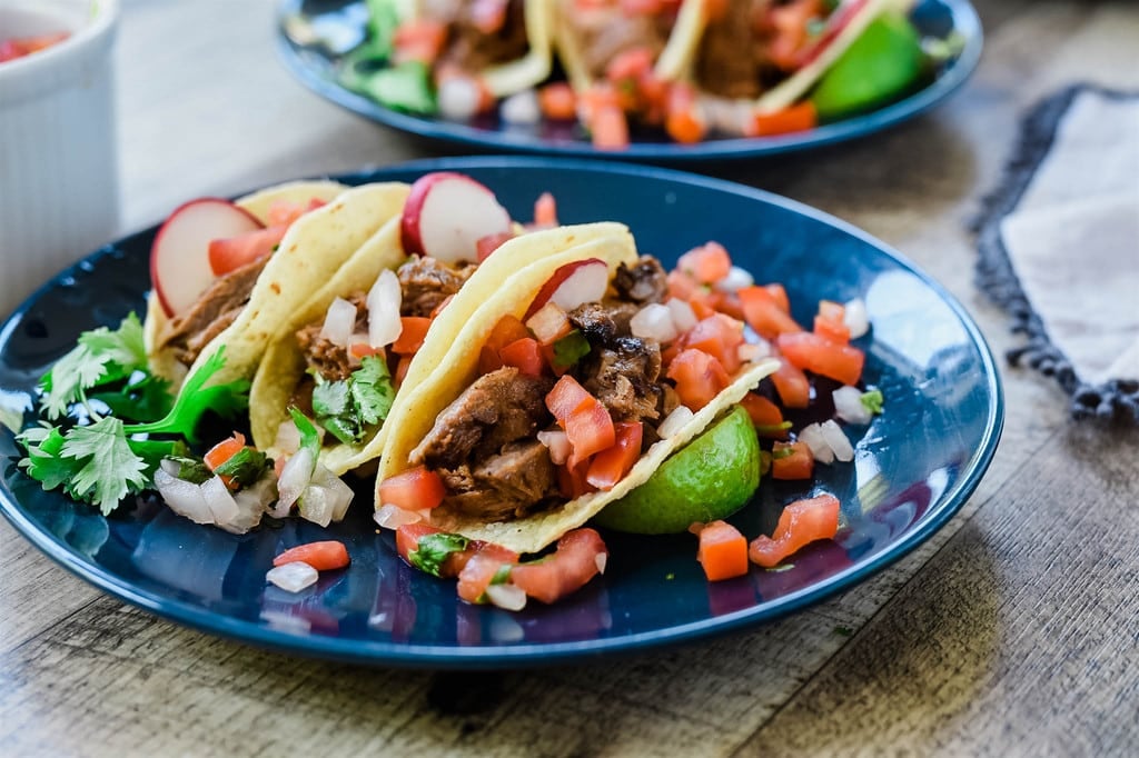 plate of skirt steak tacos garnished with cilantro tomato and radish