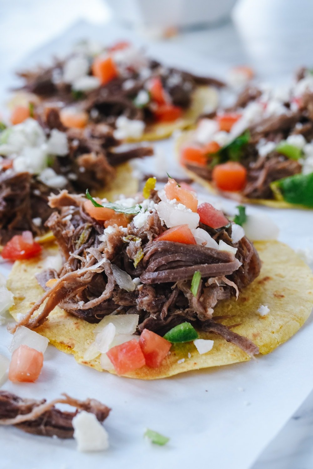 shredded beef tacos on parchment paper