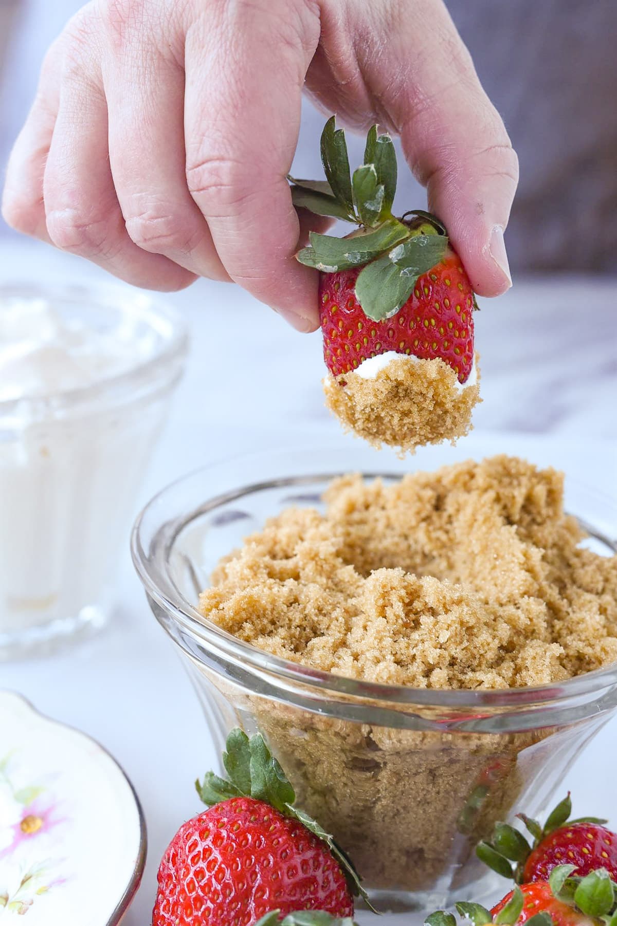 dipping a strawberry into sour cream and brown sugar