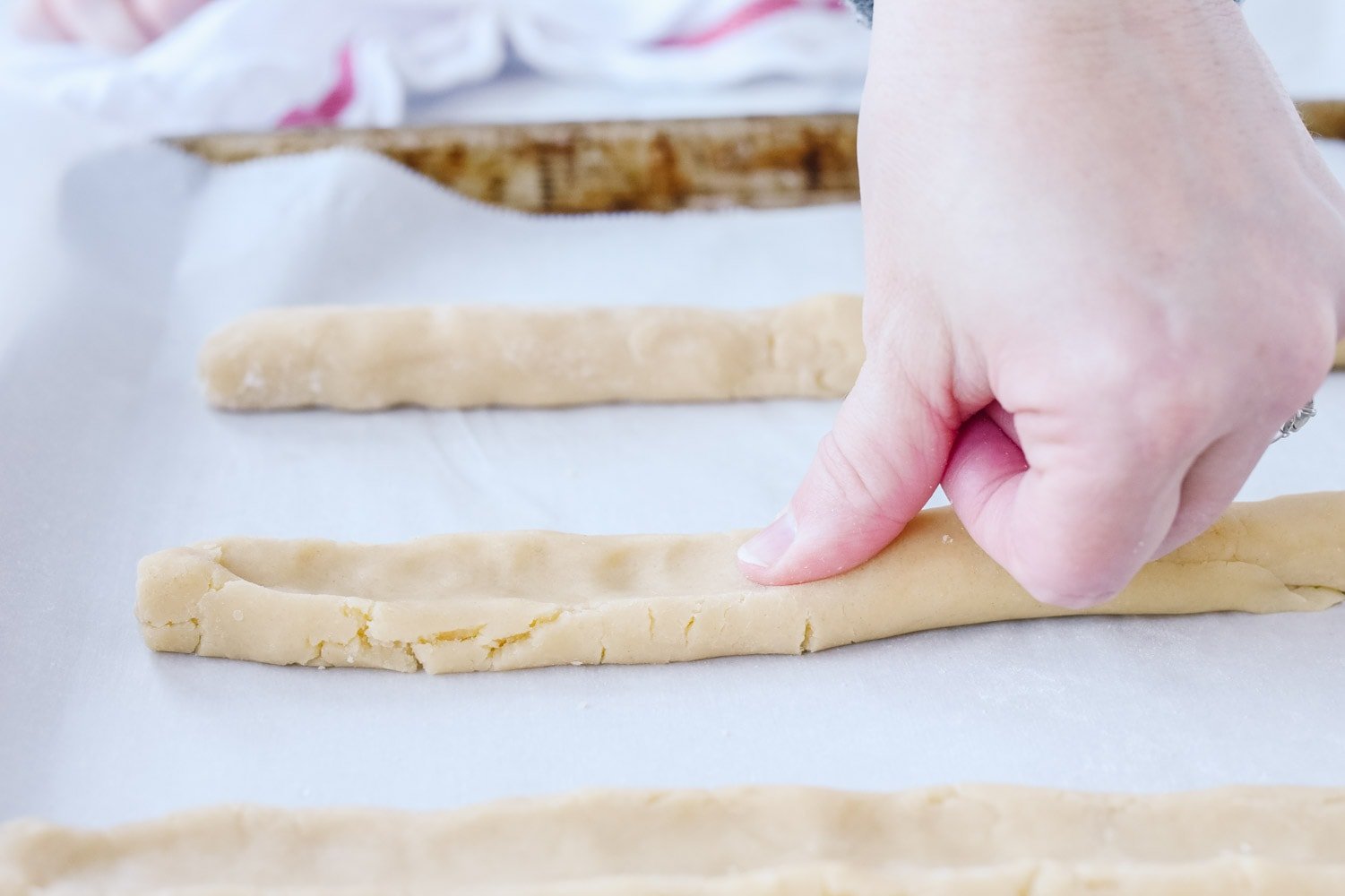 thumb pushing down on jam diagonal cookie dough