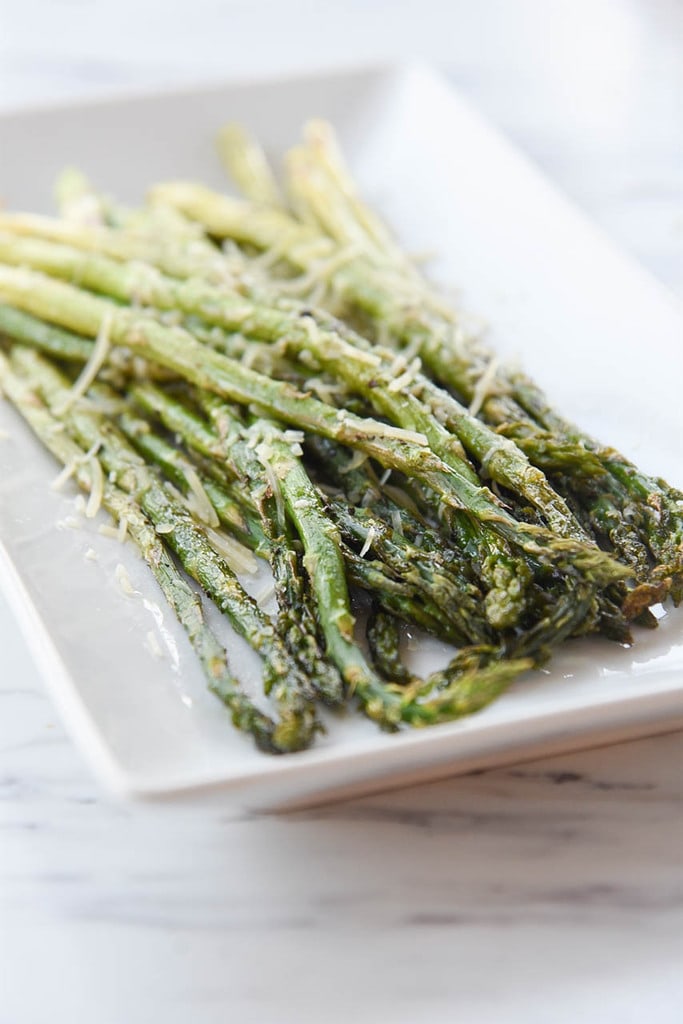 plate of asparagus with cheese on top