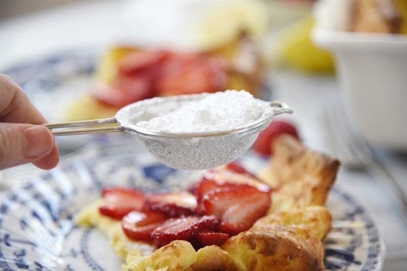 dusting Dutch Baby Pancake with powdered sugar