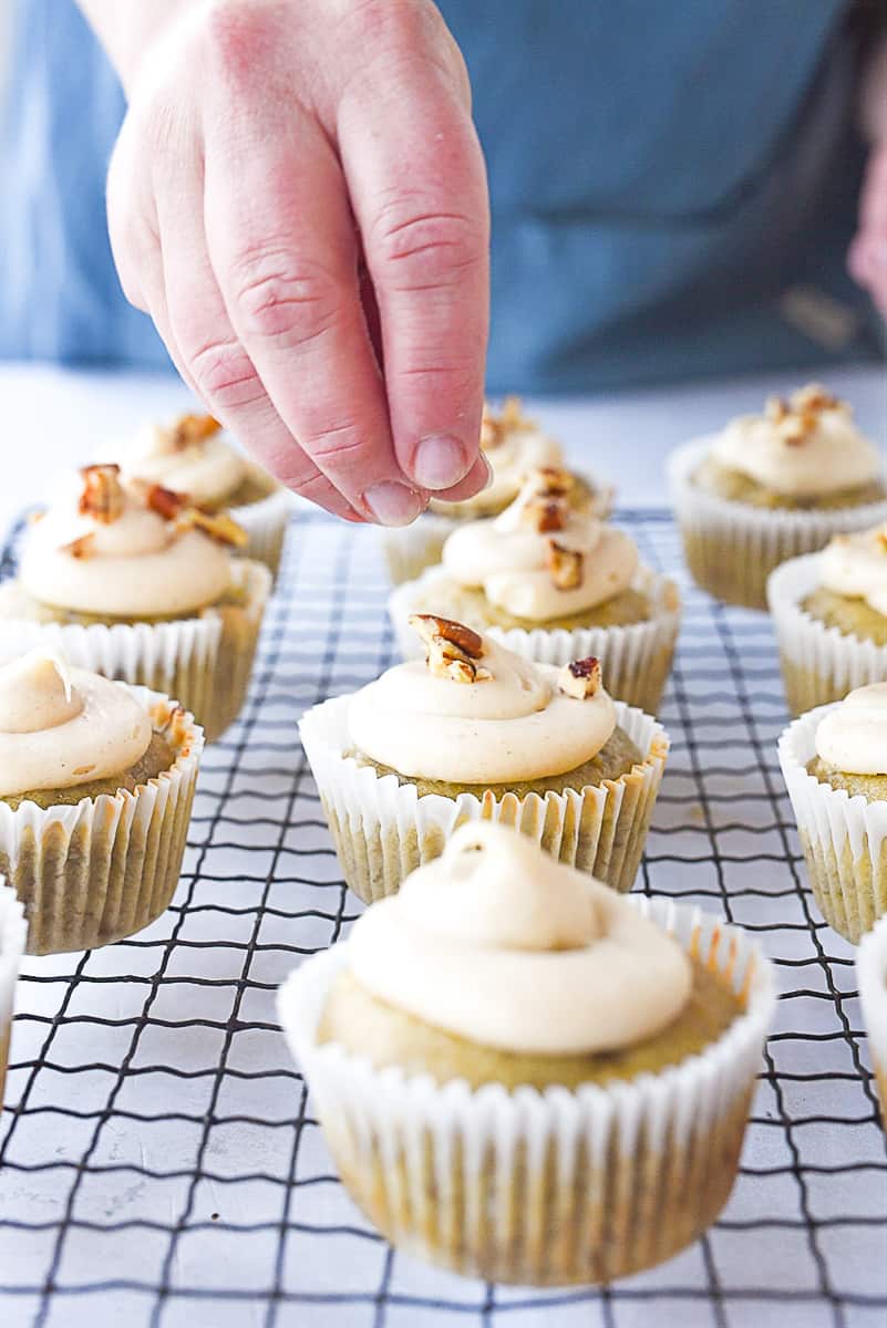 sprinkling pecans on a cupcake