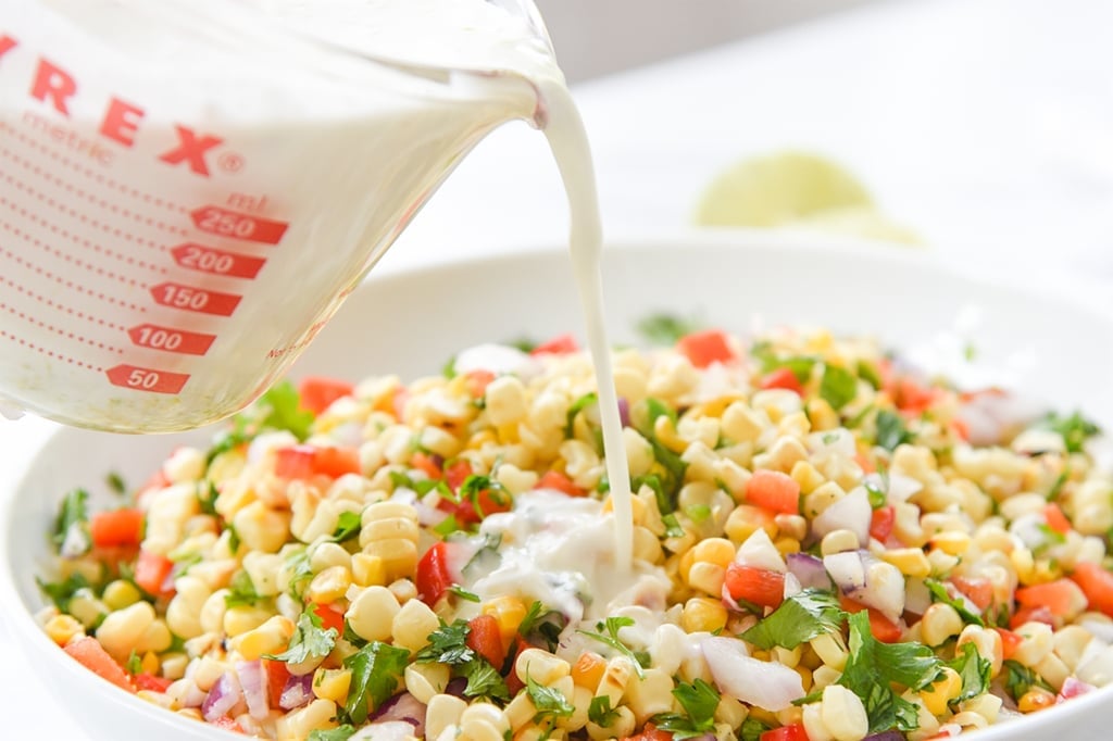 pouring dressing on roasted corn salad