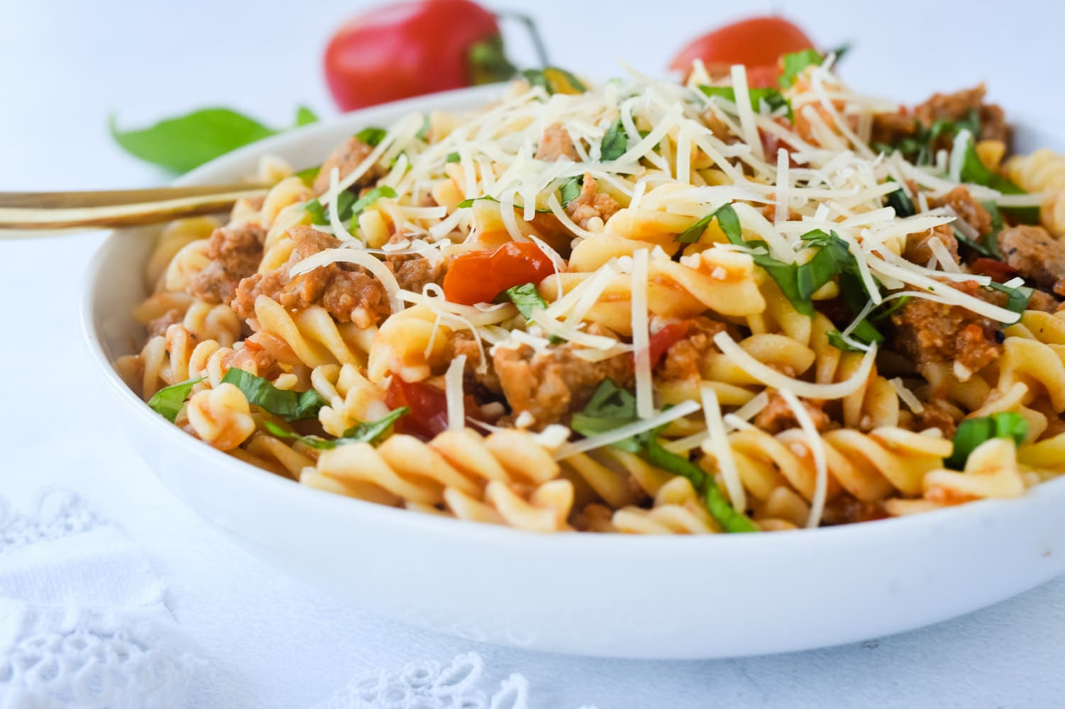 sausage and tomato pasta with parmesan cheese on top