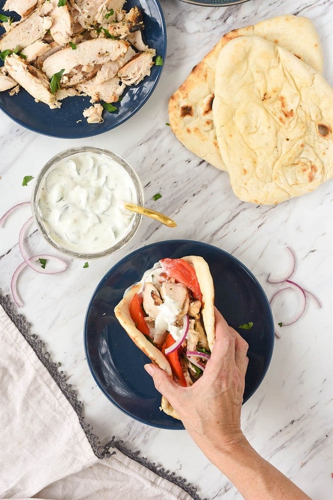 hand picking up chicken gyro from plate