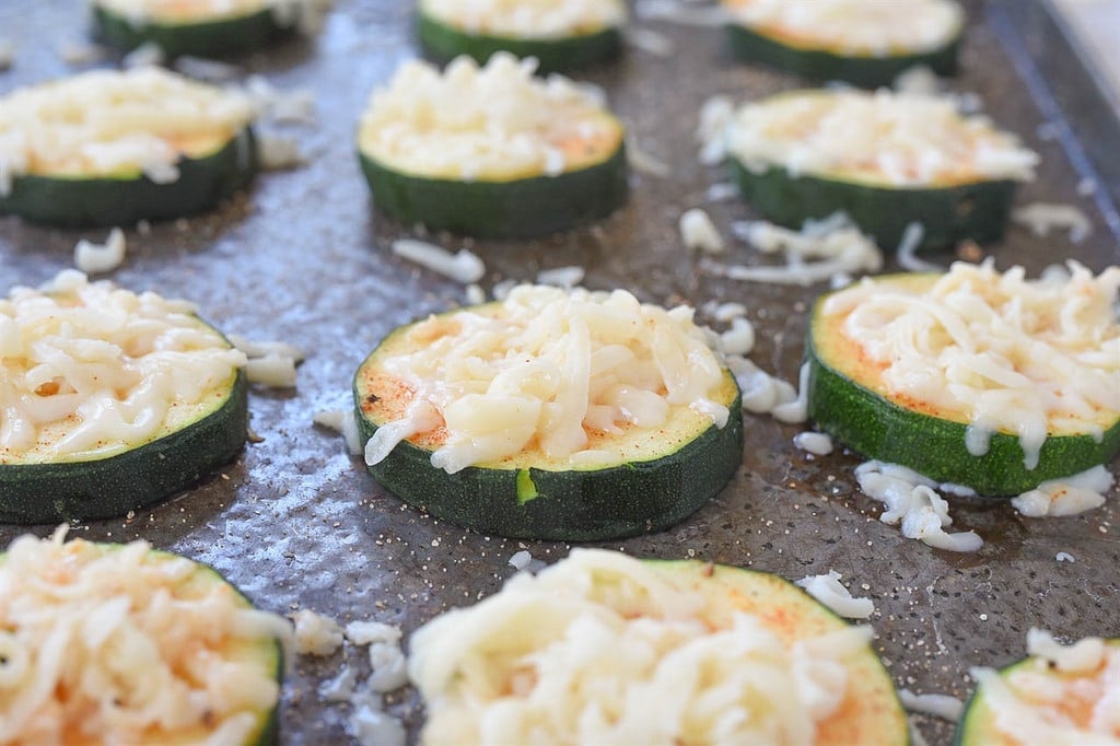 sliced zucchini topped with mozzarella on a baking sheet