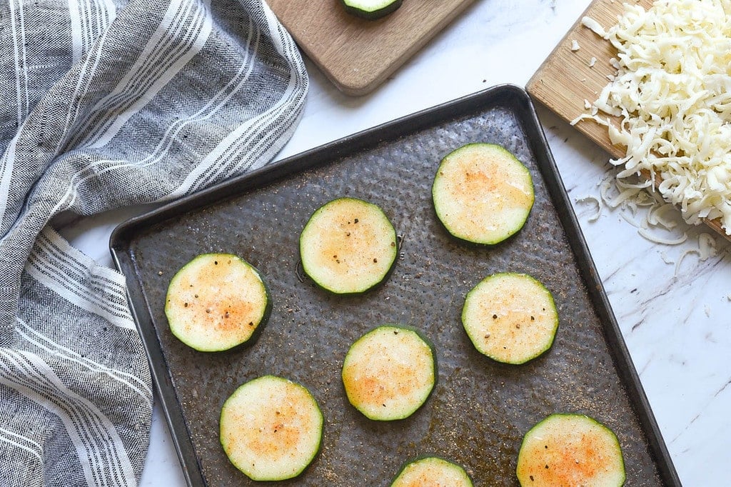 sliced zucchini seasoned on a cookie sheet