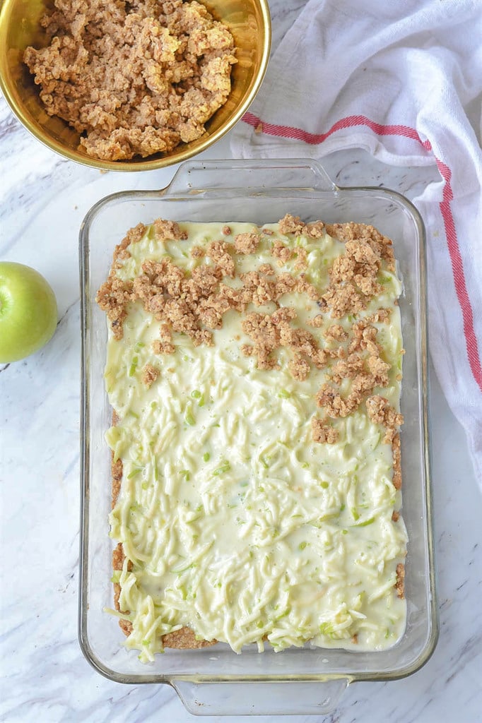 sour cream and sliced apples topped with crumble in 9 by 13 pan