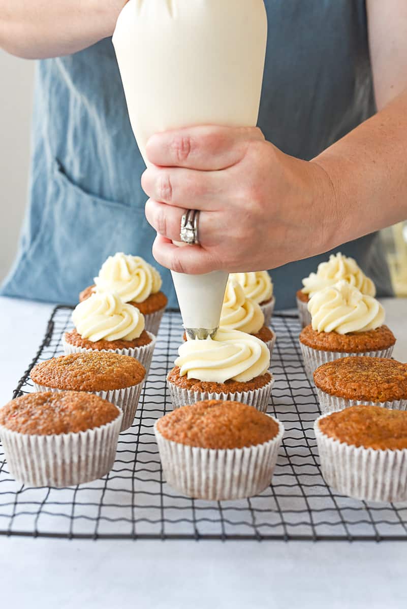 piping frosting on carrot cucakes