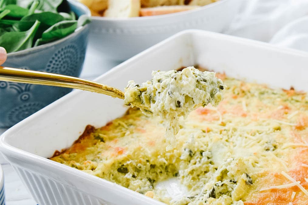 serving Spinach Artichoke Dip with a gold spoon