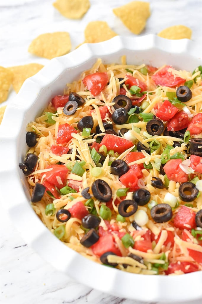 Seven Layer Dip in a white dish with tortilla chips