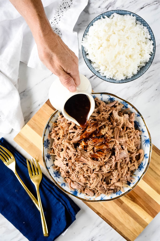 pouring BBQ sauce over Kalua Pork