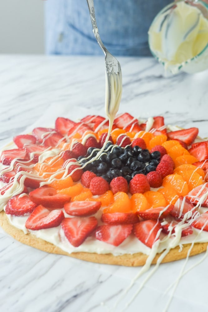 drizzling chocolate on a fruit pizza