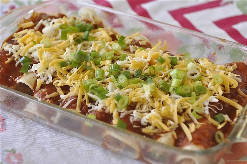 chicken enchiladas topped with homemade enchilada sauce cheese and green onions