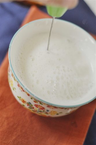 frothing milk in a mug