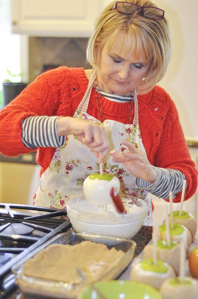 woman dipping caramel apples in white chocolate