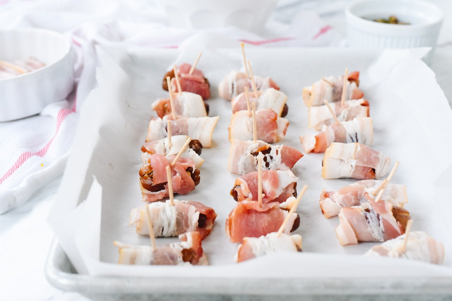 bacon wrapped dates on a baking sheet