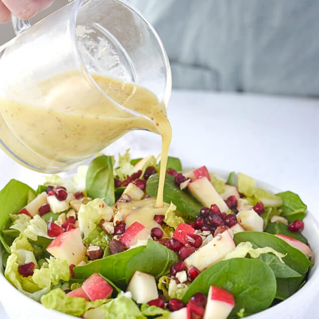 pouring salad dressing on salad