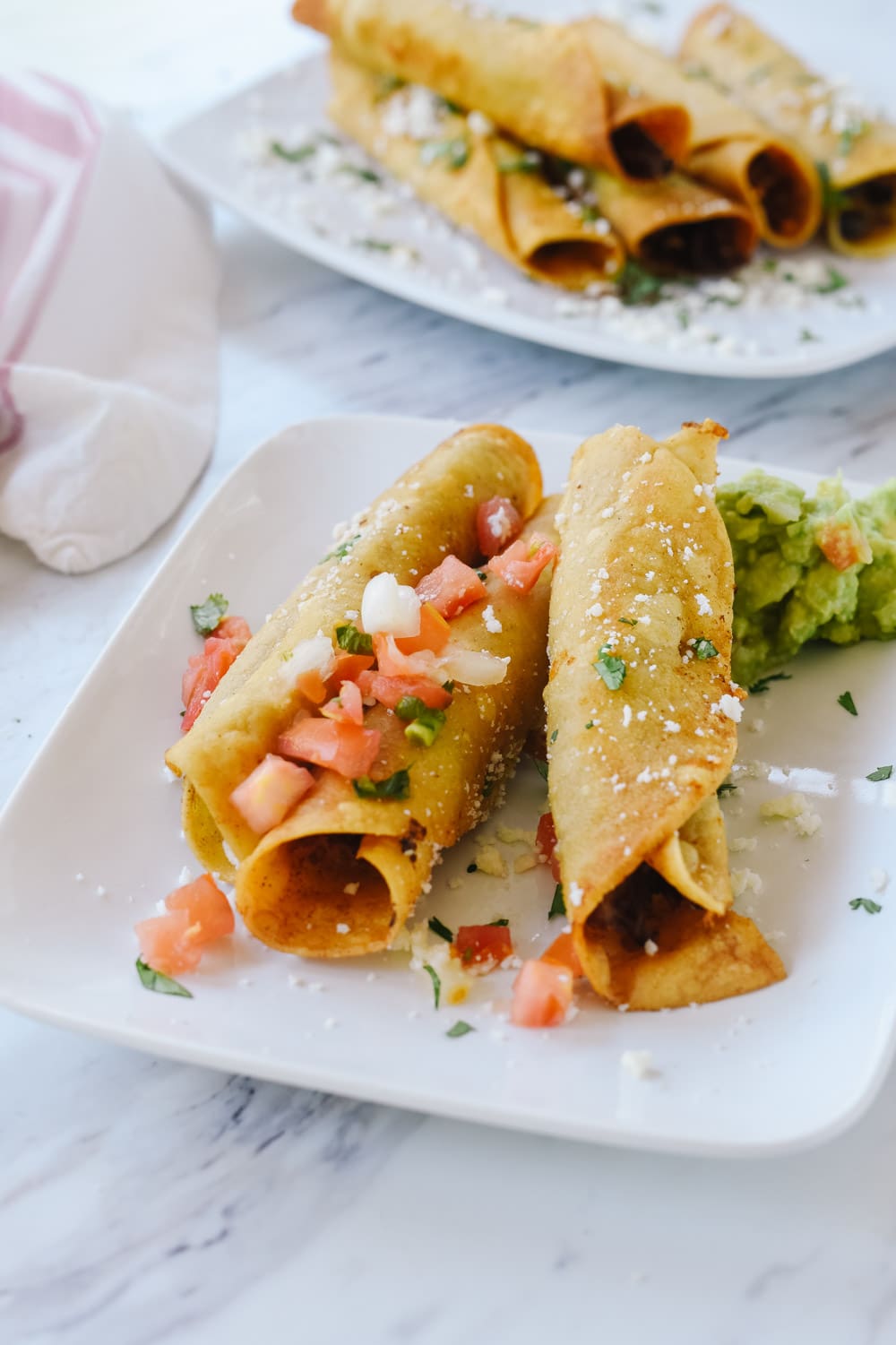 taquitos on a plate with salsa and guacamole