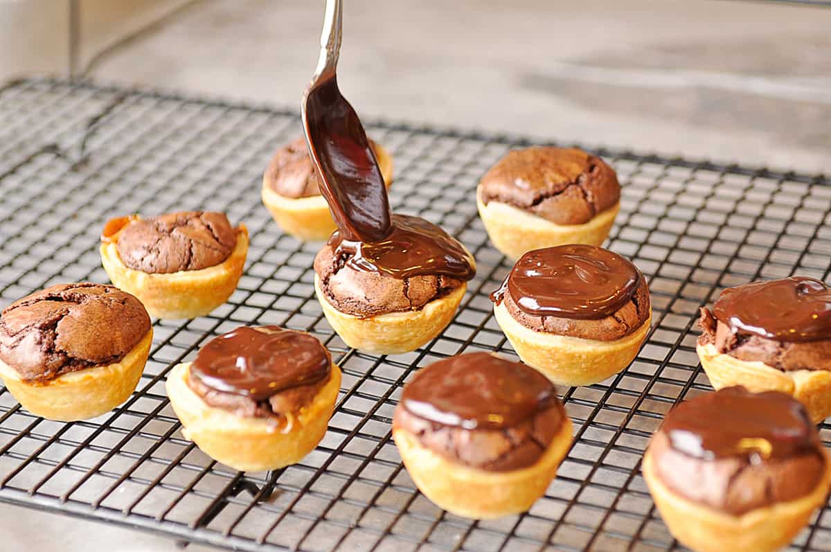 adding chocolate ganache onto brownie bites