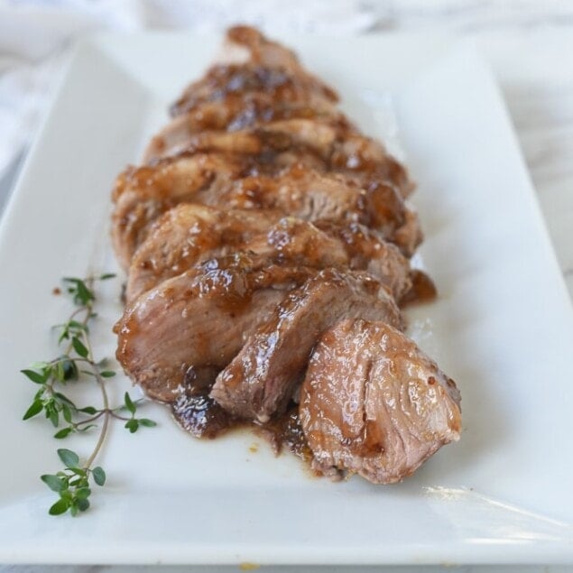 sliced fig glazed pork tenderloin on a plate.