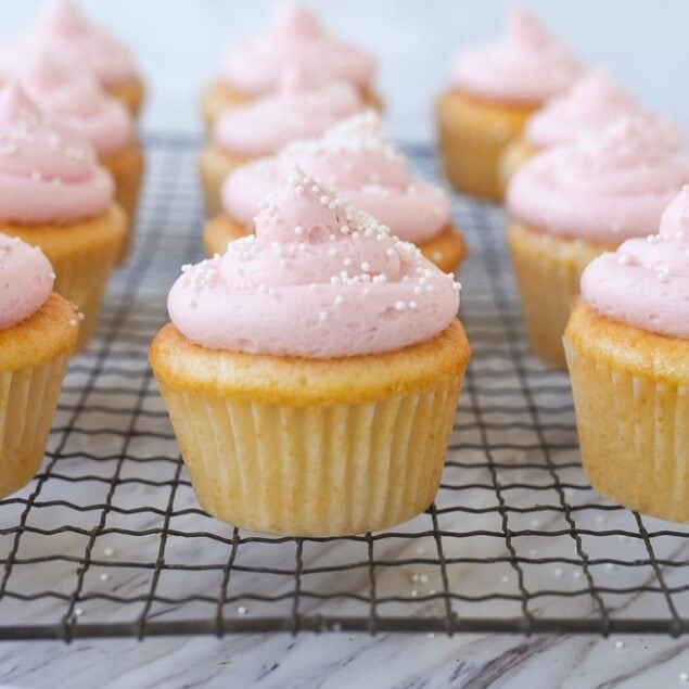 pink lemonade frosted cupcakes on a cooling rack