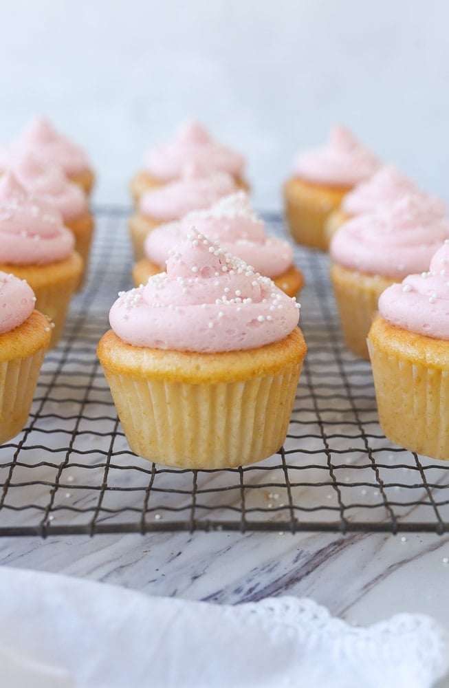 pink lemonade frosted cupcakes on a cooling rack