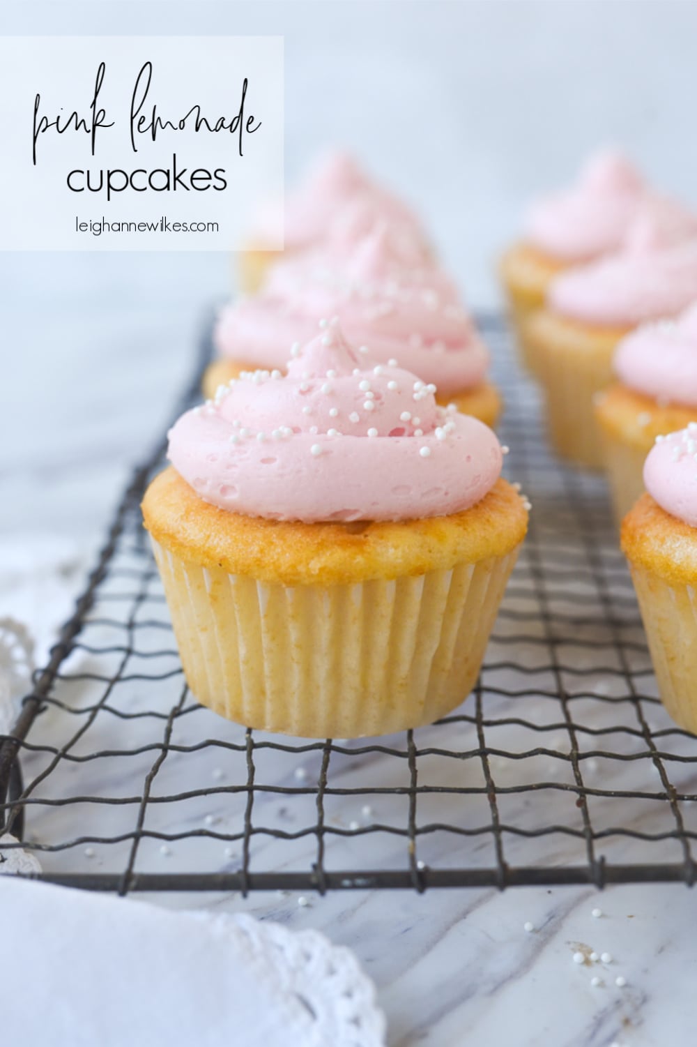 frosted pink cupcakes on a cooling rack