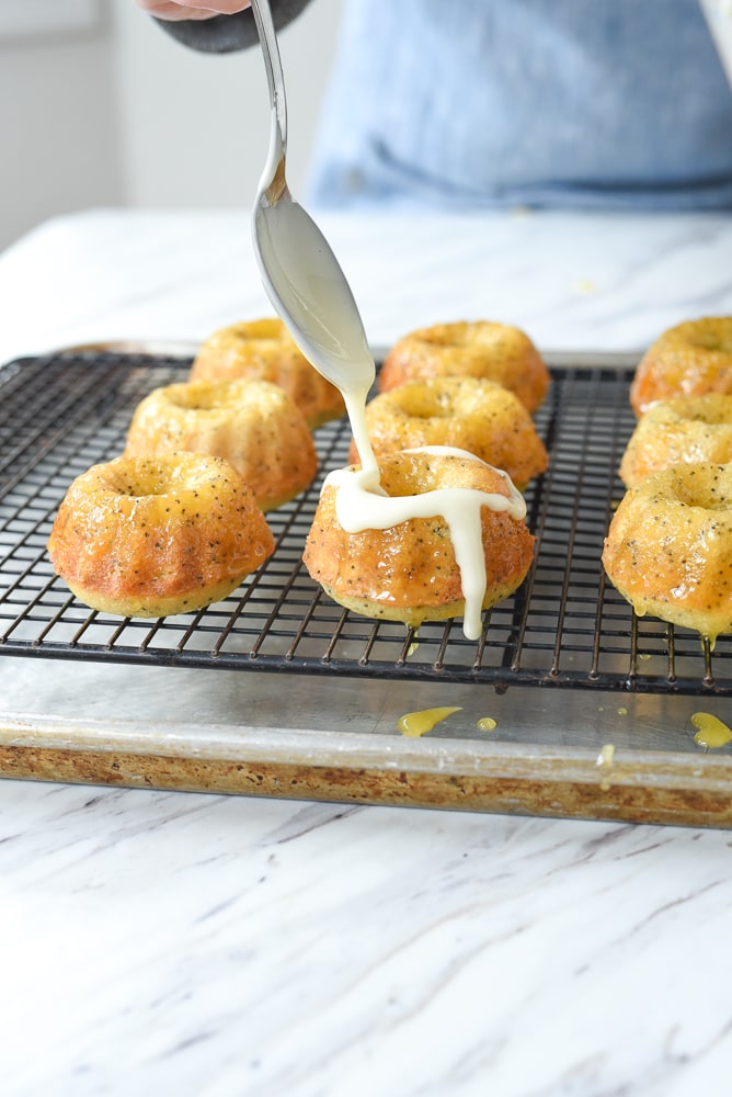 drizzling orange poppy seed cake with glaze.