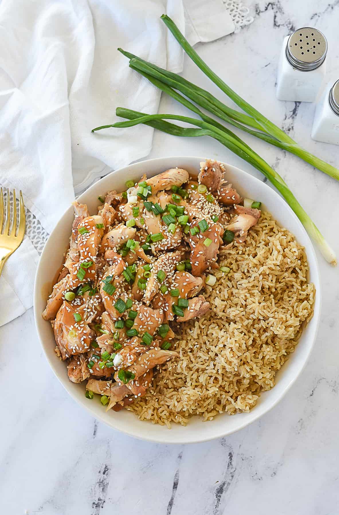 overhead shot of sesame chicken over rice in a bowl