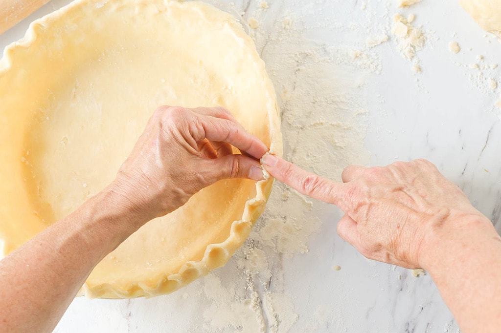 hands crimping pie crust edges