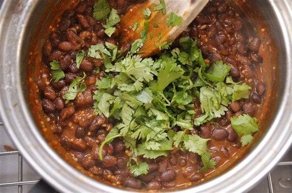 adding cilantro to pot of black beans