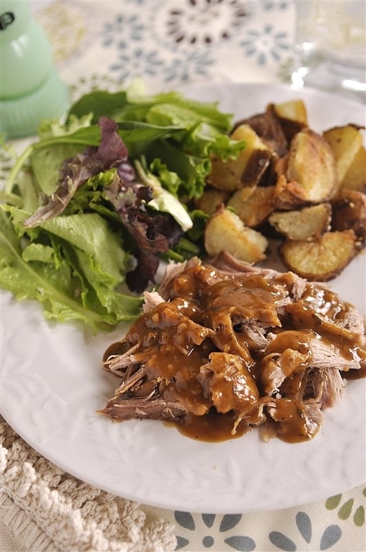 brown sugar pork tenderloin plated with salad and parmesan roasted potatoes