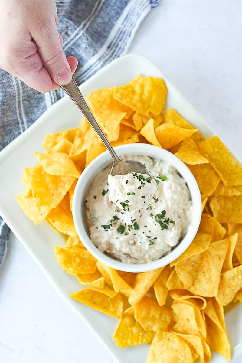 spoon and hand in a bowl of chipotle dip