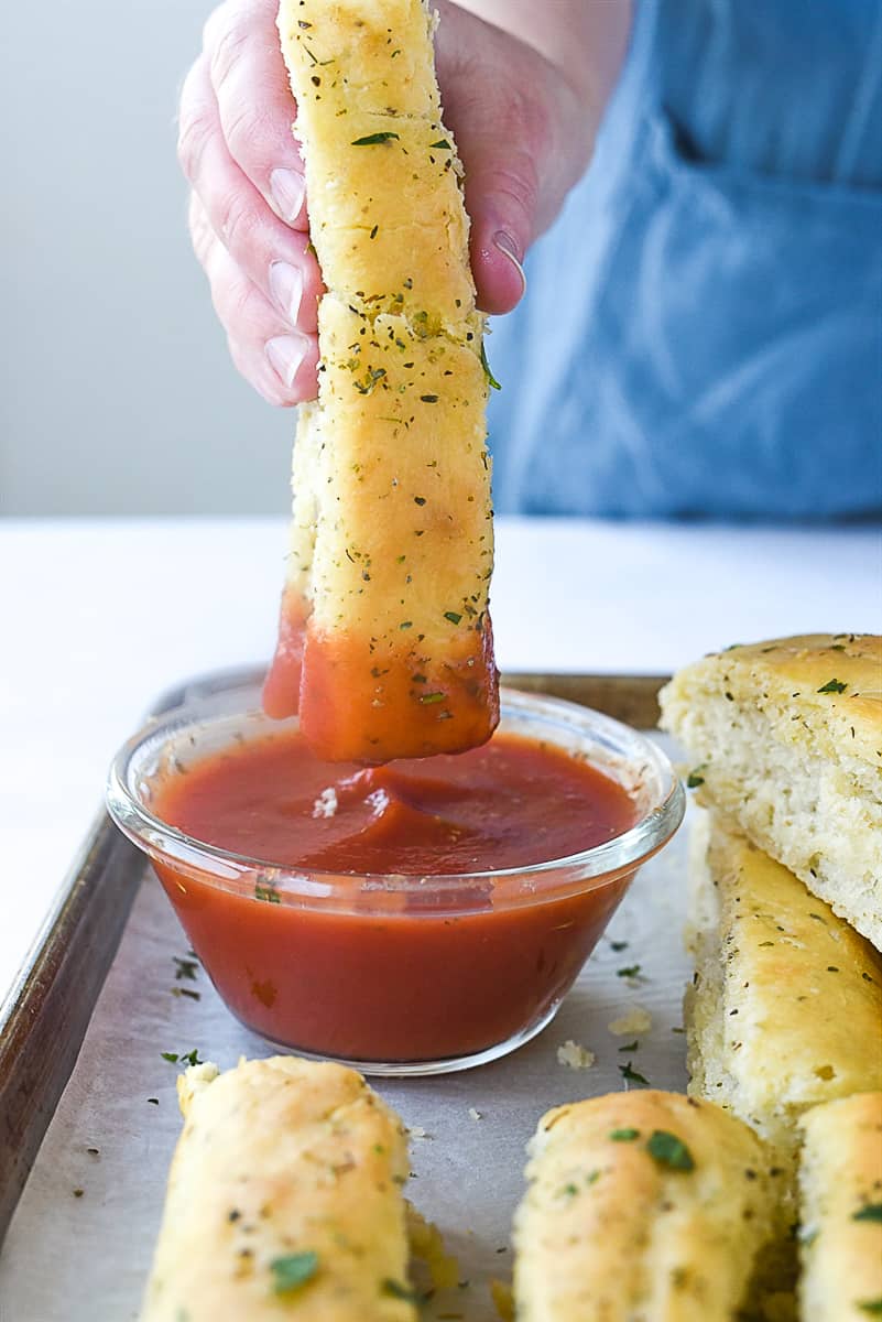 dipping breadstick into marinara sauce