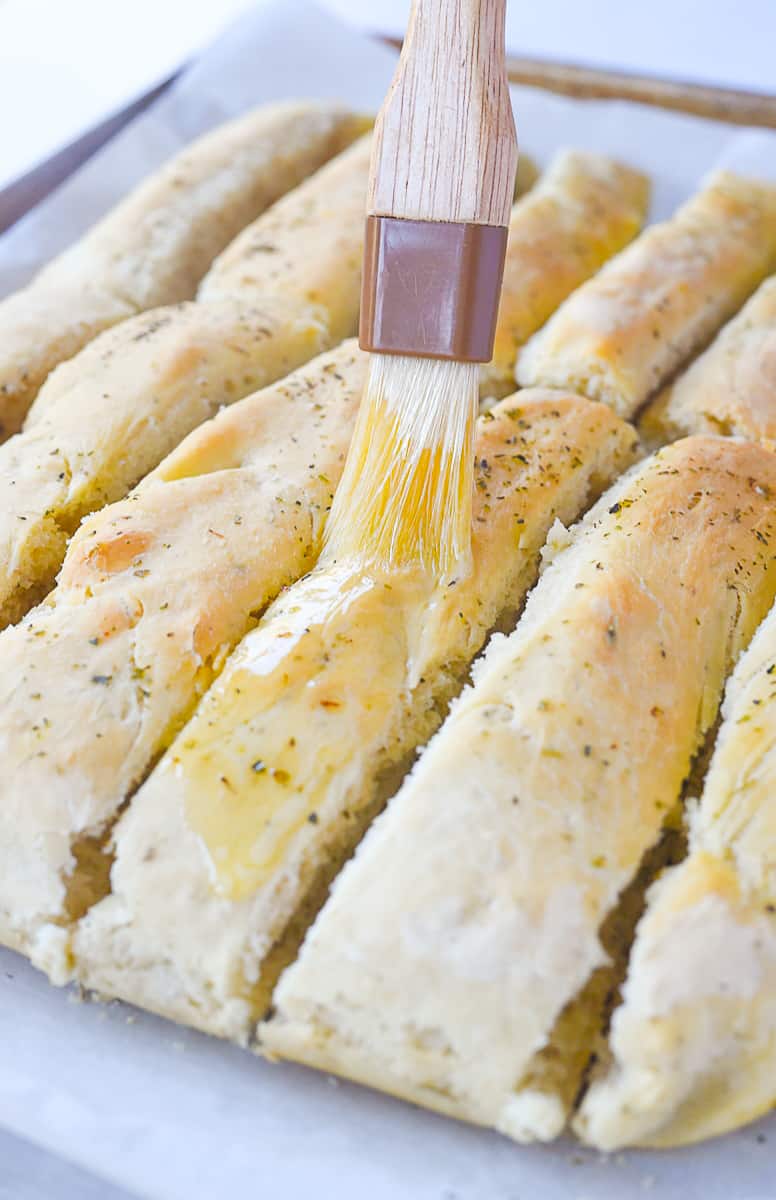 brushing breadsticks with butter