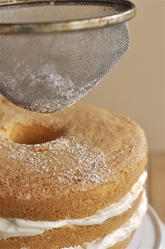 dusting layered lemon sponge cake with powdered sugar