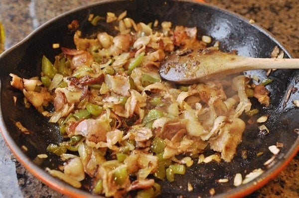 sautéing green bell peppers onion and bacon in a skillet