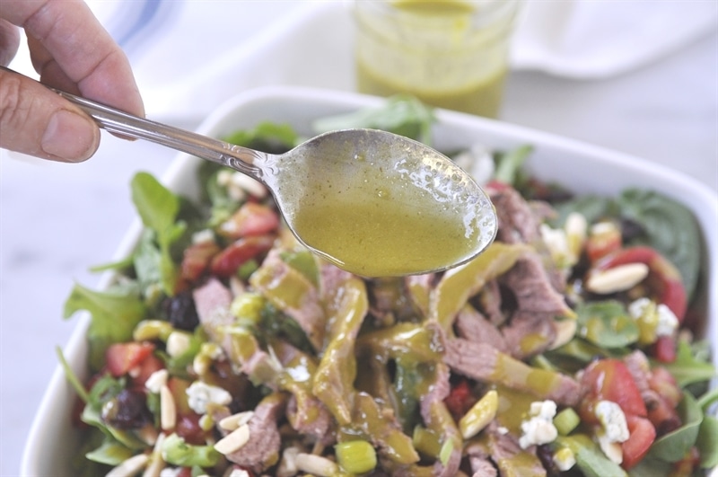 spooning dressing over steak salad