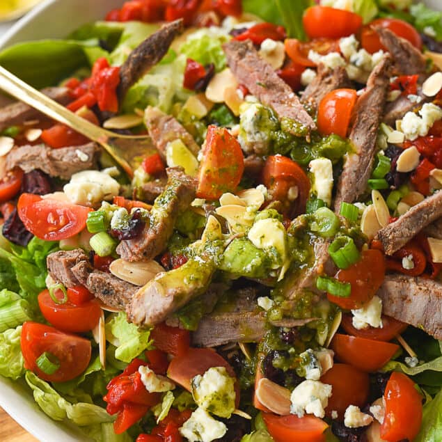 fork in steak salad in white bowl