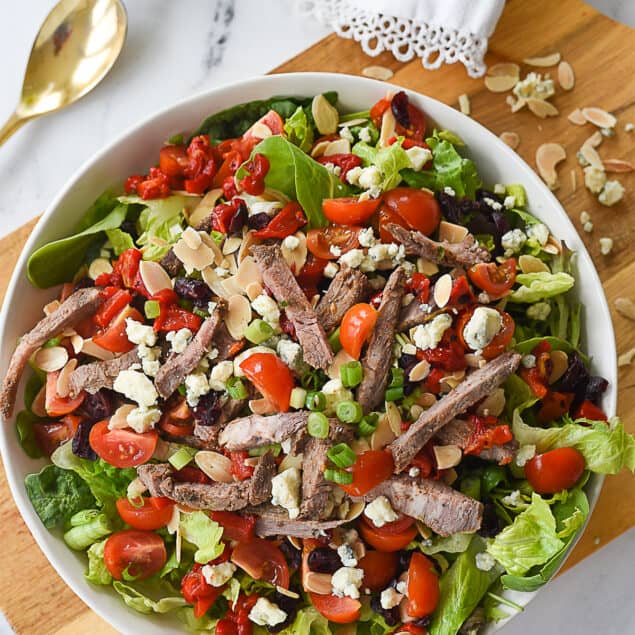 overhead shot of steak salad in a white bowl