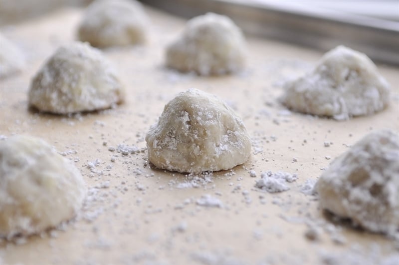 Snowball Cookies dusted with powdered sugar on a cookie sheet