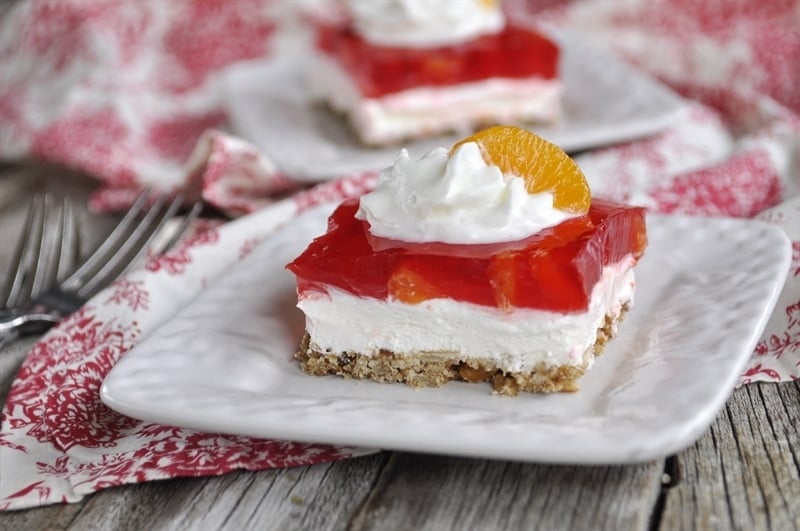 Orange Cranberry Jello Pretzel Salad topped with whipped cream and mandarin oranges