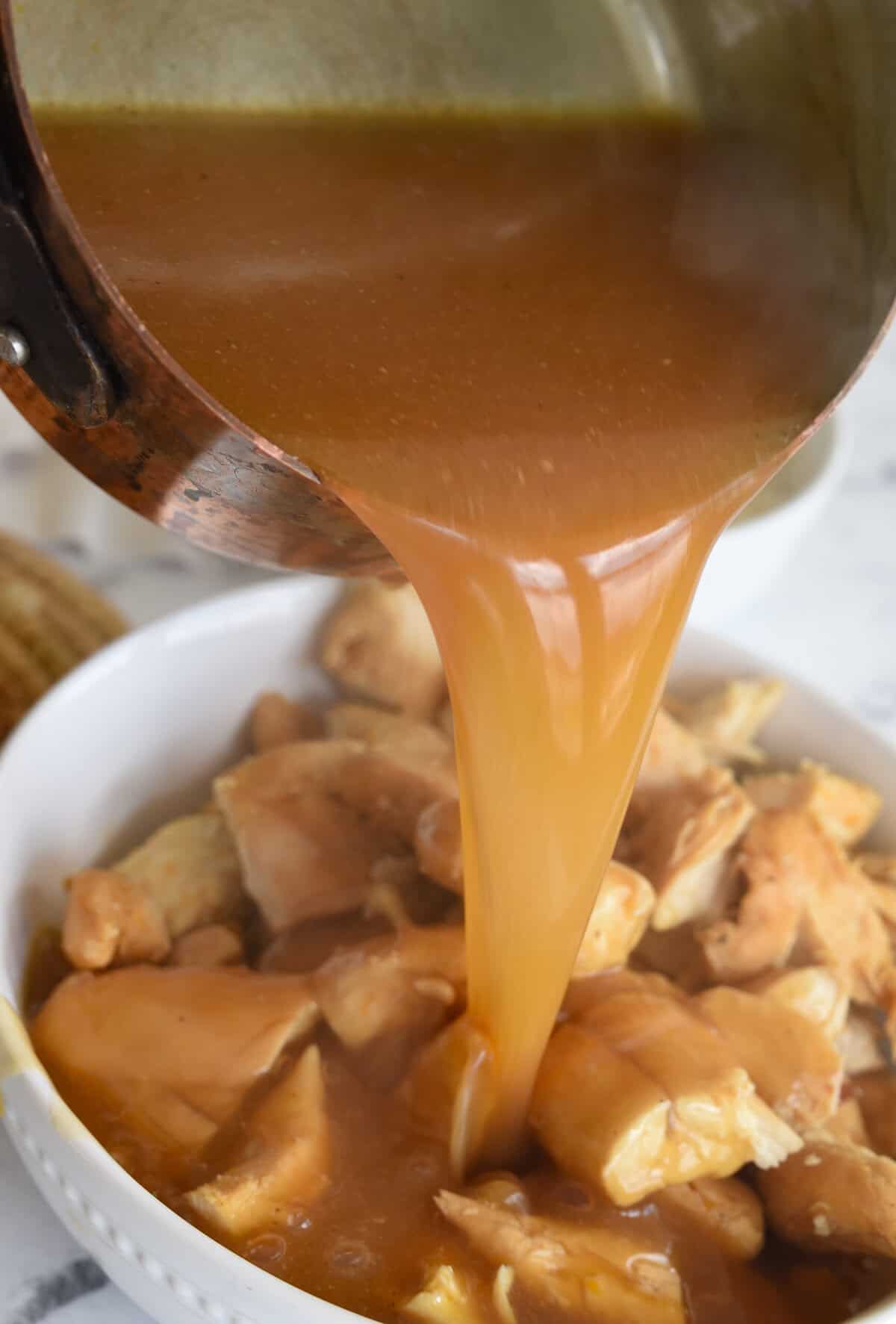 pouring sauce over orange chicken