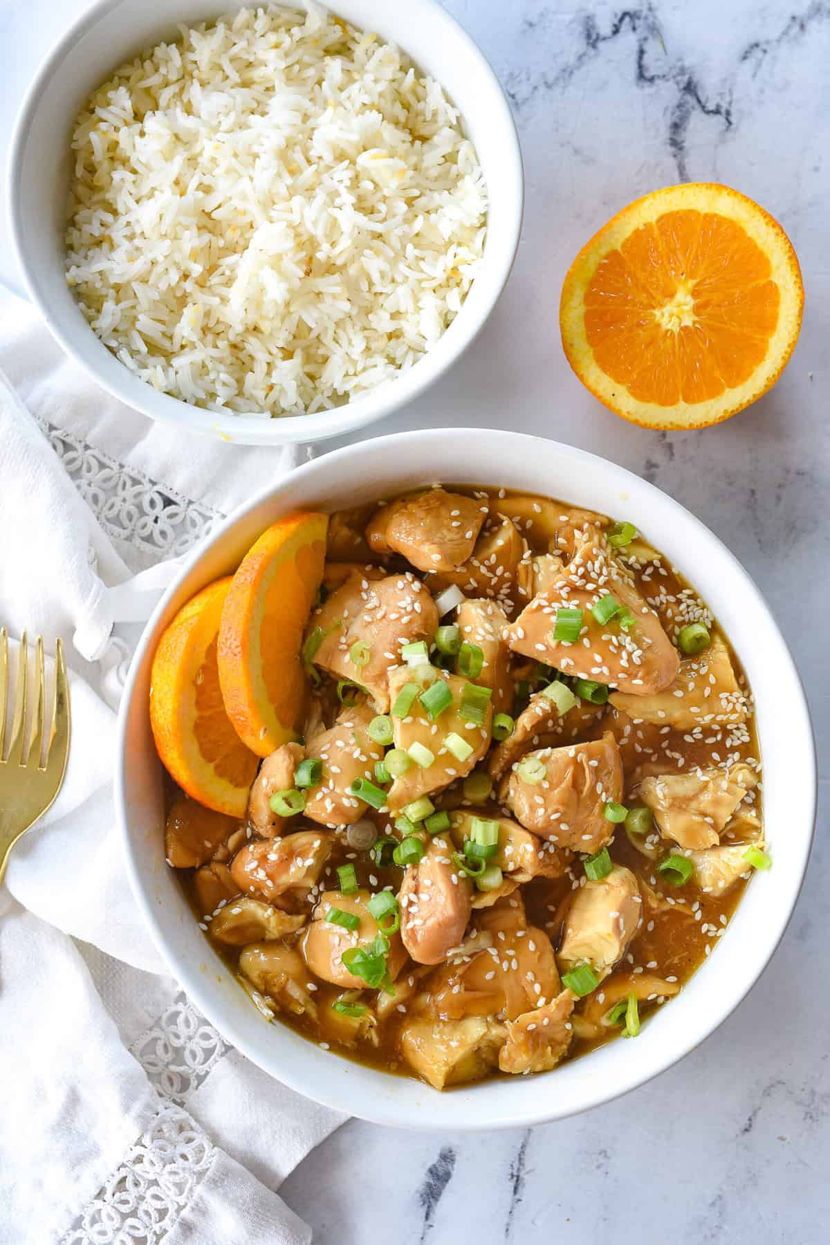 overhead shot of bowl of orange chicken and a bowl of rice