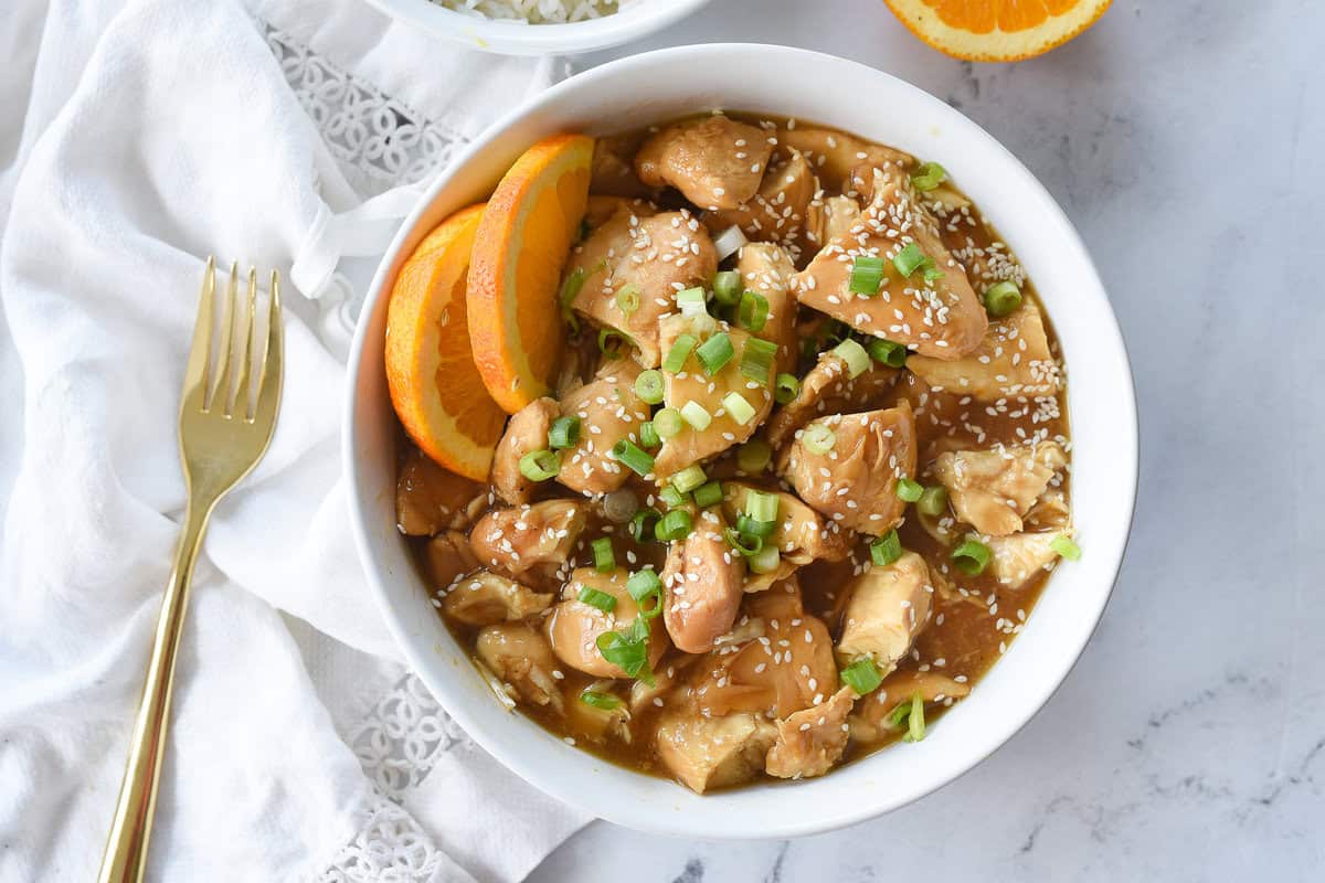 bowl of orange chicken with green onion on top