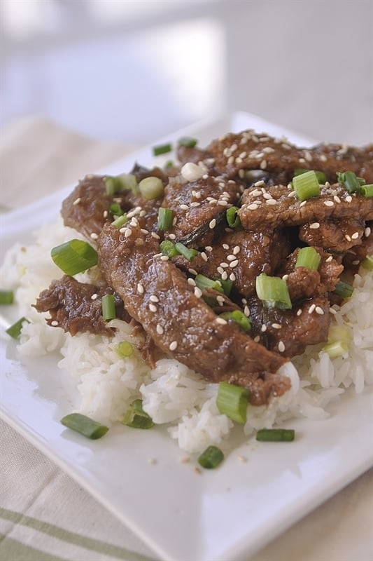 slow cooker mongolian beef topped with sesame seeds and green onions