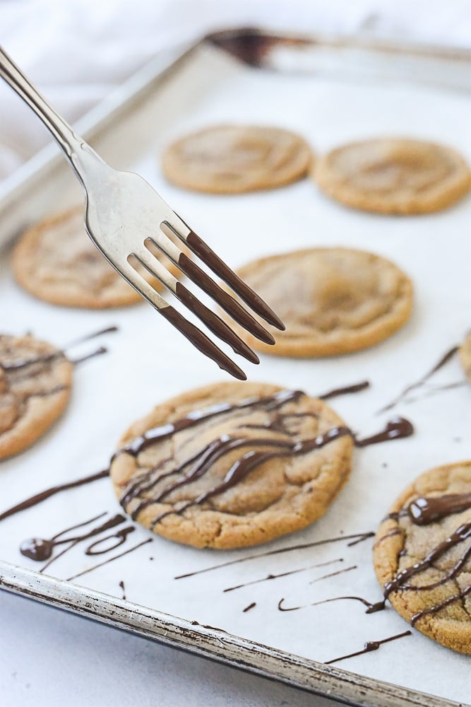 Drizzling cookies with chocolate.